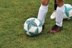 Criança chutando bola de futebol